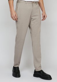 Pantaloni bej deschis, dintr-un material texturat, cu o croială slim, picioare drepte și o închidere cu nasture la talie.
