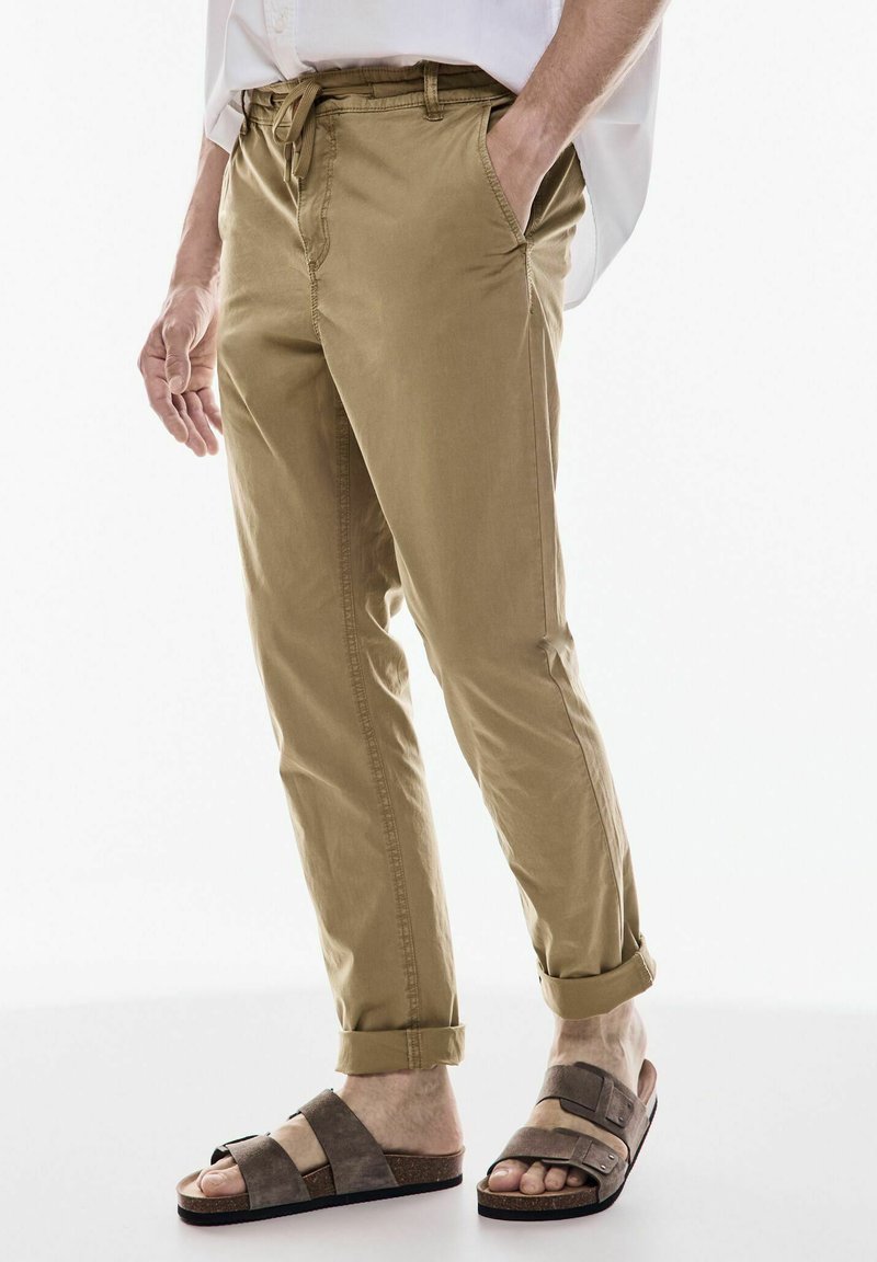 Khaki-byxor med avslappnad passform, dragsko i midjan och uppkavlade fållar. Bärs med tvåfärgade tofflor. Mjuk bomullsmaterial, avslappnad design.