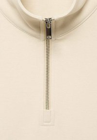 Beige half-zip sweater with a smooth texture, featuring a metallic zipper accent and a high collar design.