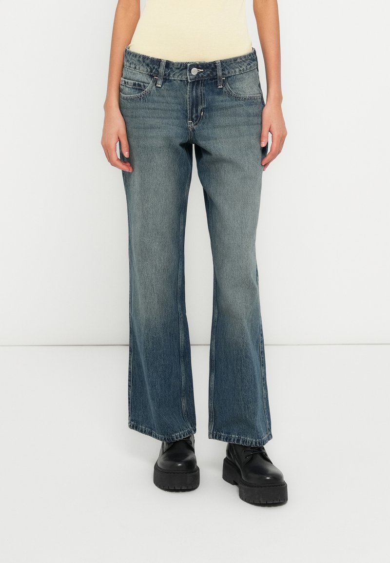 Svetlomodré široké džínsové nohavice s vyblednutým efektom; majú pás s gombíkom, dve predné vrecká a voľný strih.