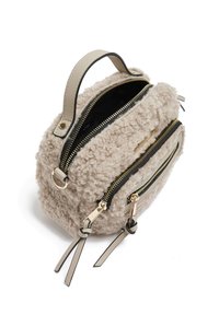 Lichtbeige nepbont tas met twee gouden ritsen, een handvat aan de bovenkant en zwarte accenten. Zachte textuur en ronde vorm met decoratieve straps.