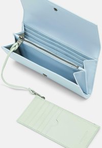 Niebieski skórzany portfel z kieszenią na zamek błyskawiczny i wieloma przegródkami na karty. Zawiera pasujący jasnozielony holder na karty z pięcioma przegródkami.