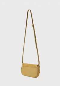 Žlutozelená kabelka přes rameno z hladké kůže s klopou z broušené kůže. Má nastavitelný popruh a minimální kovové detaily.