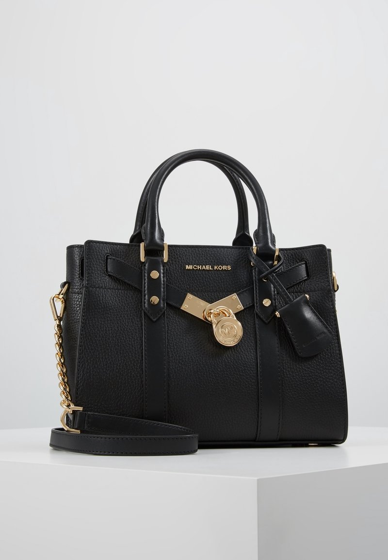 Borsa a mano in pelle nera con finitura testurizzata, dettagli in metallo dorato, chiusura a lucchetto e due manici robusti con una tracolla rimovibile.