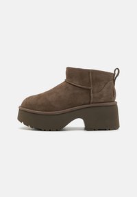 Botas de tobillo de gamuza marrón con una suela de plataforma gruesa, puntera redondeada y una lengüeta en la parte trasera; acabado texturizado y detalles cosidos.
