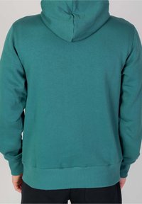 Teal huvtröja med en mjuk textur, ribbade manschetter och midja, med en sömlös baksidedesign och utan synlig branding.