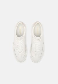 Witte leren sneakers met vetersluiting, ronde neus en gestikte details. Gouden merknaam op de binnenzool en zachte stoffen accenten.