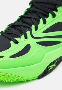 Schwarzer und neongrüner Sportschuh mit strukturiertem Gummisohle. Verfügt über ein glattes Obermaterial, lebhafte Details und Schnürdesign.