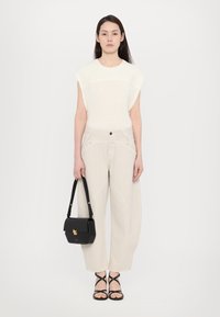 Cream knit top with cap sleeves, light beige wide-leg trousers, black handbag with gold hardware, and black strappy sandals.