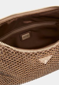 Bruine clutch tas met textuur, voorzien van een ritssluiting en een satijnen binnenkant. Beschikt over een gouden Guess-logo plaat en een klein ritsvakje aan de binnenkant.
