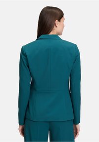 TealTailored blazer met een gestructureerde pasvorm, ingegraveerde revers en minimale stiksels. Gladde stof met lange mouwen en een ventilerende achterkant.