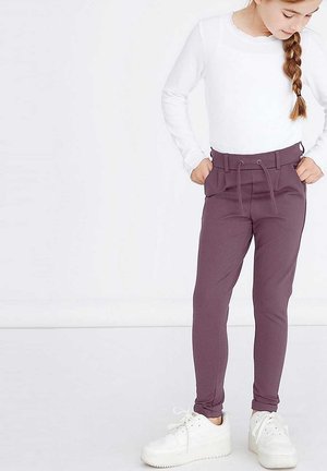 Leggings violets avec taille à cordon et poches latérales, associés à un haut blanc à manches longues et des baskets blanches.