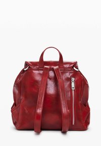 Rucksack aus rotem Leder mit glänzender Oberfläche, verstellbaren Trägern, einem oberen Griff und einer seitlichen Reißverschlusstasche. Weiches, strukturiertes Design.