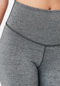 Höga grå leggings tillverkade av textil, elastiskt tyg med platta sömmar och en smidig midjeband för komfort och stöd.
