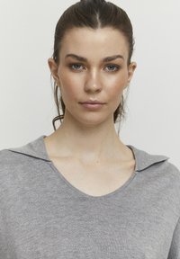 Grå striktop med V-hals og diskret kravedetalje. Blød tekstur med en let afslappet pasform, der præsenterer et minimalistisk design.