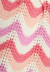 Coperta all'uncinetto con un motivo a zigzag in tonalità di rosa, bianco e blush. Realizzata in morbido filato con una superficie lavorata a maglia testurizzata.