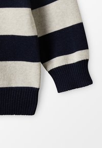 Marinblå och krämfärgad randig stickad tröja med ribbade ärmslut och nederkant, slät textur och en avslappnad design.