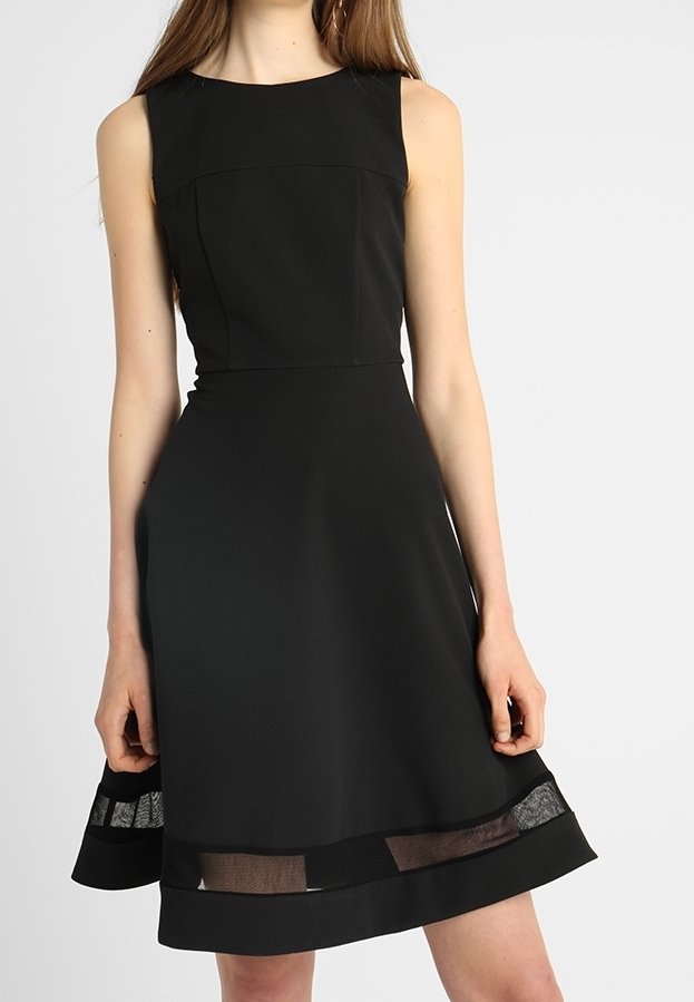 Robe noire sans manches avec un corsage ajusté, une jupe évasée et des panneaux en maille au bas, fabriquée dans un tissu lisse au design épuré.