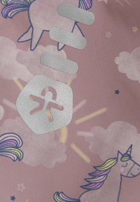 Rosa tyg med tecknade enhörningar, moln och stjärnor. Silverfärgad metall och en texturerad logotyp synes tydligt mot den mönstrade bakgrunden.