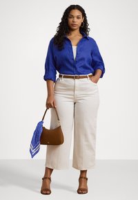Camisa de linho azul, calças largas brancas de cintura alta, cinto de pele castanho, mala castanha com um lenço azul e sandálias castanhas com tiras.