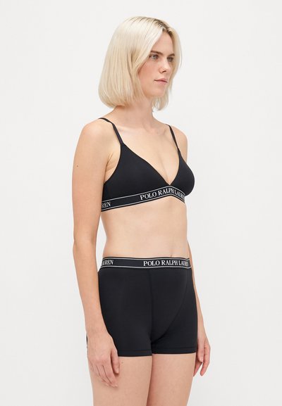 Svart ribbet bralette med justerbare stropper og logobånd. Kombinert med matchende svarte shorts med logobånd i livet. Glatt tekstur.