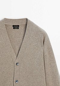Cardigan en laine beige avec un col en V profond, deux boutons foncés et des manches longues, posé à plat sur un fond blanc.