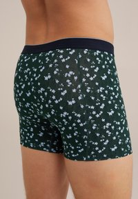 Sötétzöld férfi boxer alsó, világoskék virágmintával, tengerészkék derékszíjjal és testhezálló fazonnal. Puha, rugalmas anyag.