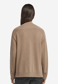 Brauner Strickpullover mit lockerer Passform, geripptem Saum und Rundhalsausschnitt. Die Textur wirkt weich und gemütlich, ideal zum Layering.