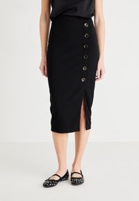 Svart blyertskjol med hög midja, sidoklyfta och sex stora knappar fram. Tillverkad av ett mjukt tyg med en åtsittande silhuett.