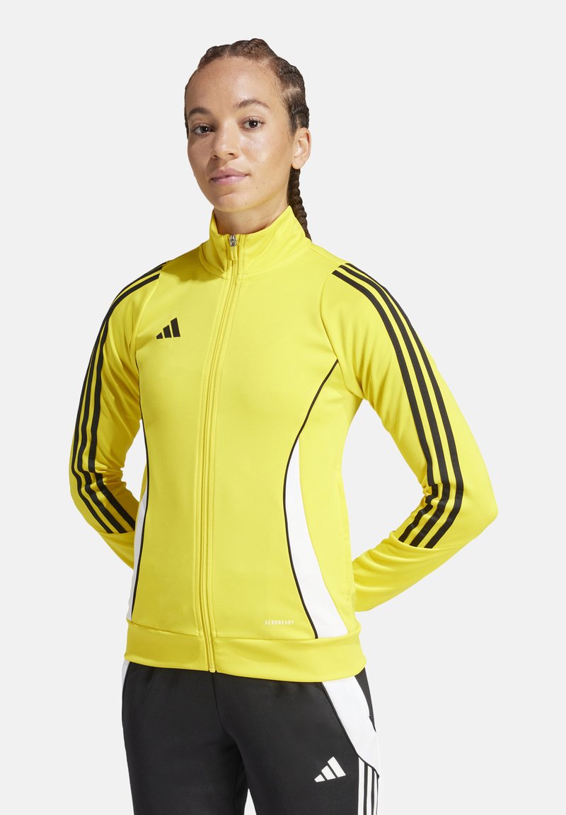 Geel sportjack met ritssluiting van gladde stof, voorzien van zwarte contrasterende strepen en een witte zijaccent. Inclusief "AEROREADY" label.