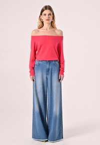 Fuchsia Schulterfreies Oberteil mit langen Ärmeln, kombiniert mit hellblauen Jeans im weit geschnittenen Design, die einen ausgefransten Saum und eine lockere Passform aufweisen.