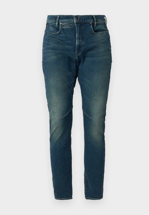 Tumedad sinine teksased ja slim fit lõikega, millel on tõmblukk, viie tasku disain ja jalgeosas peened kulunud alad tekstuuriks.