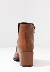 Ruskeat nahkaiset nilkkurit, joissa pyöreä kärki, keskikorkea blokki-heel ja sivussa vetoketju. Sileä pinta, vähäiset ompelut.