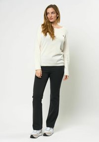 Lys kremfarget langermet genser med rund hals, kombinert med svarte bukser og grå joggesko med hvite og beige detaljer.