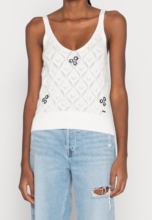 Witte gebreide tanktop met een diepe V-hals, voorzien van diamantpatronen en marineblauwe bloemen details. Ribgebreide zoom en schouderbanden.