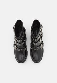 Bottes de cheville en cuir noir avec plusieurs boucles en argent et détails en œillets. Texture lisse, bout rond et fermeture éclair.