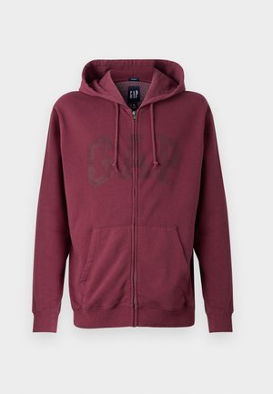 Felpa con zip color marrone bordeaux, dotata di tasca frontale e cappuccio con lacci, caratterizzata da un discreto logo GAP sul petto.