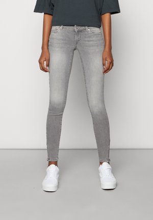 Jean skinny gris avec un ourlet effilé, en tissu denim. Associé à des baskets blanches pour un look contrasté.
