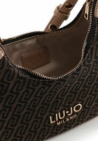 Braune Handtasche mit Muster, Reißverschluss, goldfarbenen Beschlägen und einem hellbraunen Innenfutter. Verfügt über ein Logo-Patch und eine glatte Textur.