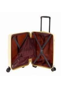 Maleta rígida en color crema con una superficie texturizada. Interior forrado en tela burdeos que cuenta con un bolsillo con cremallera y correas elásticas de sujeción.