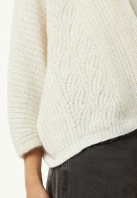 Biały sweter z dzianiny z textured wzorem i ściśniętymi brzegami. Luźny krój i miękka tkanina, w połączeniu z ciemnoszarymi dżinsami.