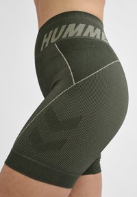 Zielone szorty z prążkowanej tkaniny z elastycznym paskiem w talii, z napisem "HUMM". Akcentowane wzorem w zygzak i kontrastowymi detalami ściegów.