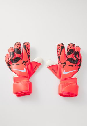 Pair of red and black patterned Nike goalie gloves with white accents and wrist straps, laid flat on a white surface.