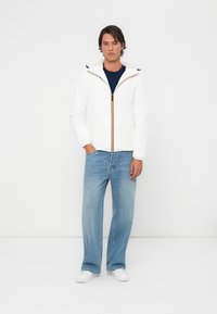 Hvid zip-jakke med hætte, med en guld lynlås, parret med lyseblå jeans og hvide sneakers. Enkel design og afslappet pasform.