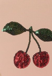 Tessuto rosa con un design di ciliegie caratterizzato da paillettes rosse per i frutti e paillettes verdi per le foglie, il tutto contornato da una cucitura nera.
