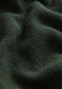 Tissu texturé en vert foncé, présentant un motif à côtes avec des lignes verticales marquées, doux au toucher et légèrement extensible.
