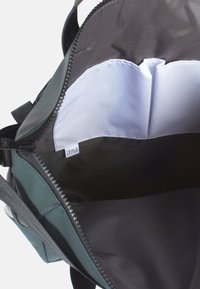 Groene leren tas met een ritsluiting. Interieur heeft een zwarte stoffen voering en een witte zak. Verstelbare schouderband bevestigd.