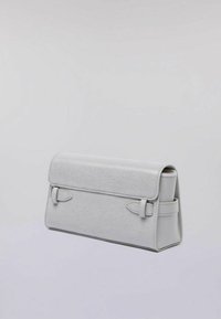 Clutch bag in pelle grigia con un design strutturato, forma rettangolare piatta, chiusura a patta e cinture decorative laterali. Texture liscia.