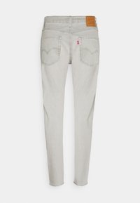 Ljust grå denimjeans med slim fit, med en tagg på midjebandet, två bakfickor och subtila sömnadsdetaljer.