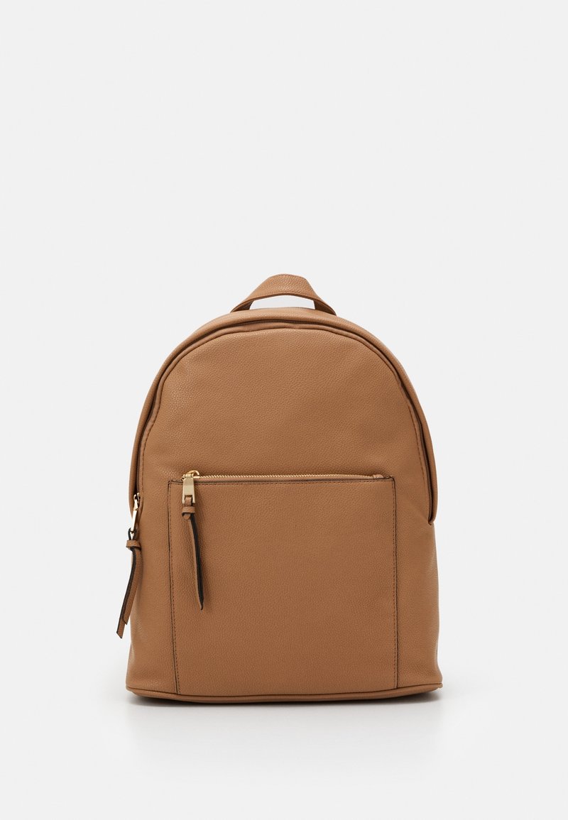 Sac à dos en cuir tan avec une forme arrondie, une surface texturée, une poche zippée à l'avant et une poignée de transport sur le dessus.